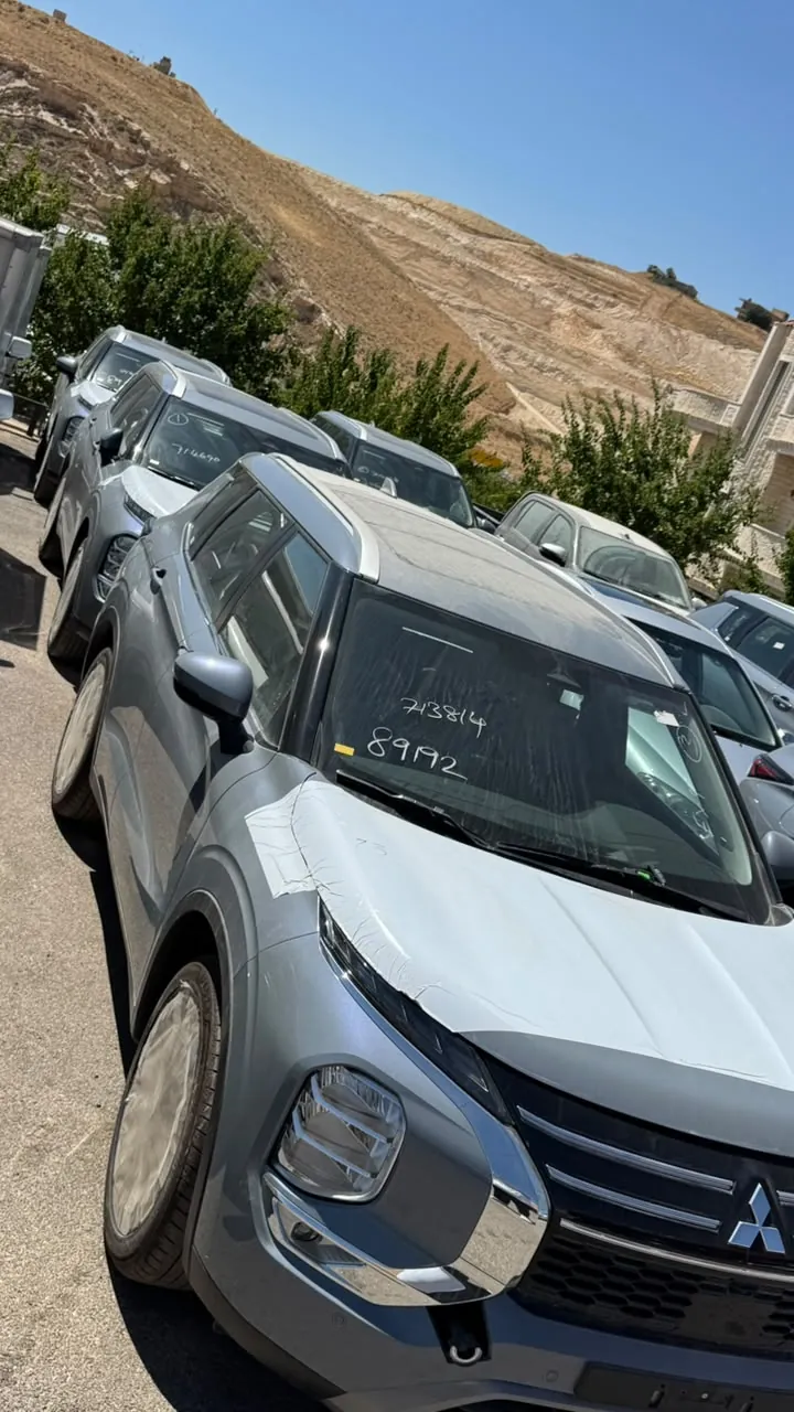 سيارة دفع رباعي رمادية اللون متوقفة مع سيارات أخرى في ساحة خارجية تحت أشعة الشمس